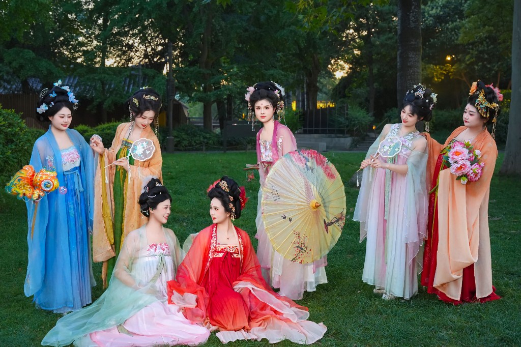 七位穿着不同颜色汉服的姐妹在草地上合影